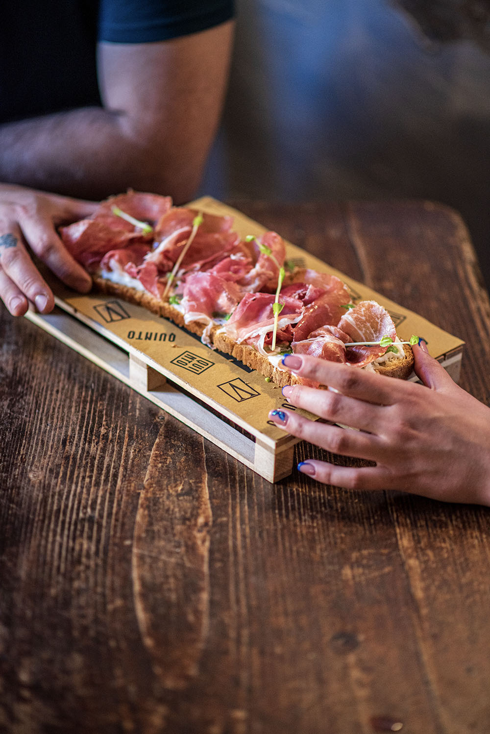 brueschetta con prosciutto crudo con mani alle estremità che la afferrano